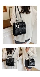 Close-up of black bow backpack with pearl charm showing single shoulder and crossbody styles