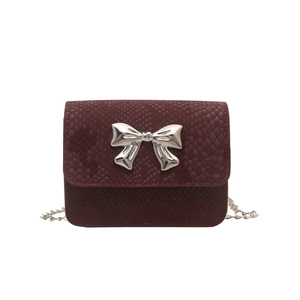 Burgundy faux snakeskin crossbody bag with a large silver bow and chain strap