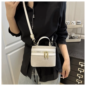 Detailed view of canvas and leather crossbody bag with golden dual zippers and strap