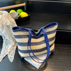 Blue and white striped straw tote bag with leather handles for summer beach outings