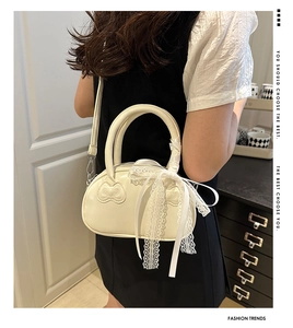 Detail of cream white leather bag featuring a bow relief and lace handle decoration