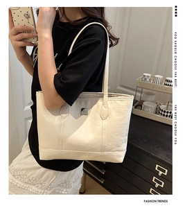 Close-up of cream PU leather tote bag with embossed animal patterns and metal plate