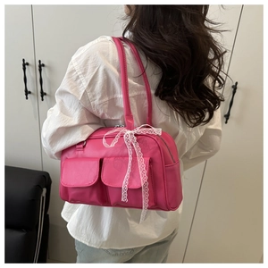 Détail du sac à bandoulière rose avec nœuds en dentelle blanche et deux poches frontales