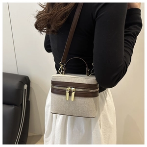 Detail of canvas box bag with brown leather trim and golden double metal zippers