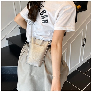 Detail of silver bucket crossbody bag with textured leather on a modern backdrop