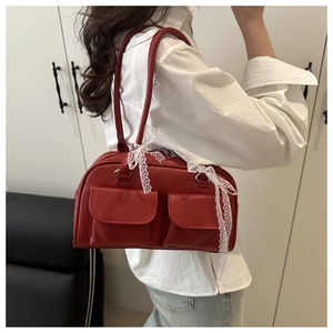 Détail du sac à épaule en cuir rouge avec poches utilitaires et nœud en dentelle blanche