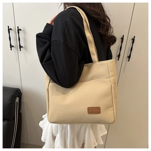 Close-up of beige canvas tote bag with leather patch on model for daily commute