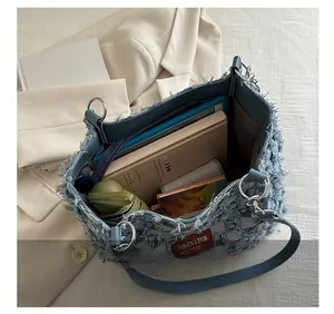 Macro detail of spacious denim tote bag interior showing capacity with books and umbrella