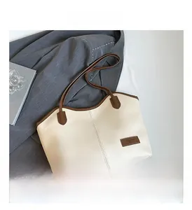 Close-up of cream tote bag featuring brown straps, PU leather texture and Fashion label