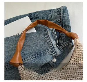 Detail der gewebten Strohtasche mit braunem Lederriemen und Knotendesign