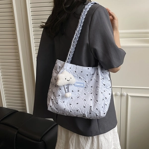 Quilted light blue tote bag with black bow embroidery and woven shoulder strap