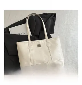 Detail showing cartoon embossed pattern and metal logo plate on beige faux leather tote bag