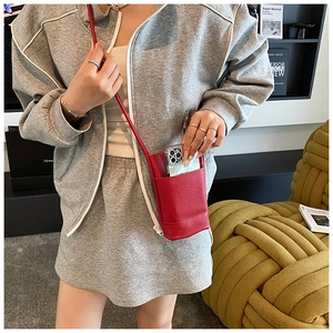 Close-up of red lychee grain leather crossbody phone bag with slim shoulder strap