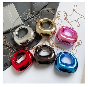 Flat lay of metallic evening bags in six colors with chain straps on a minimalist desk