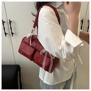 Détail du sac rouge en cuir PU avec poches à rabat et nœuds en dentelle blanche
