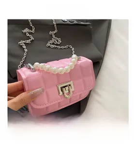 Detail of pink quilted leather handbag featuring a large pearl handle and silver chain strap