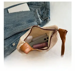 Detail der gewebten Strohtasche mit braunen Ledergriffen und glattem Metallreißverschluss