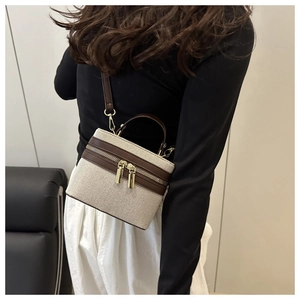 Detail of canvas and leather mini box bag showing dual metal zippers and gold hardware