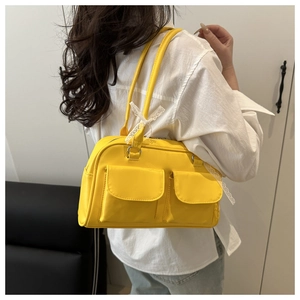 Détail du sac à main jaune avec poches à rabat et ruban en dentelle blanche sur l'anse