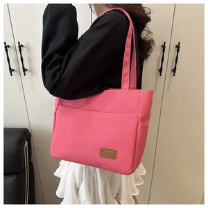 Detail of rose pink canvas tote bag showing side pocket and brown leather brand patch