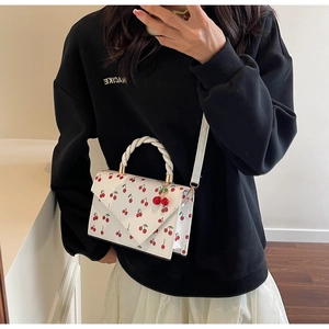 Detail of white cherry print handbag with woven handle and 3D cherry charm