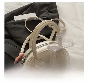 Close-up of cream shell bag featuring a lace bow and stylized character patch detail