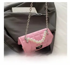 Detail of pink quilted mini bag with pearl handle, chain strap, and metal buckle