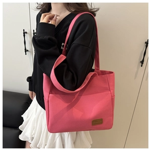 Pink canvas tote bag detail showing the front pocket, leather patch and wide shoulder strap