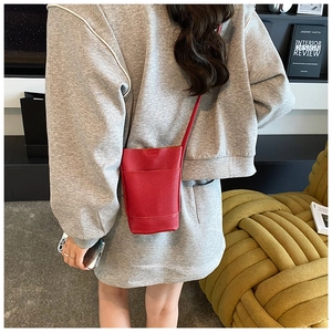 Rear view of a model wearing a red pebbled leather mini crossbody phone bag on a slim strap