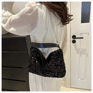 Detail of black sequin crossbody bag with silver chain strap shown on person