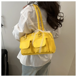 Detail of yellow shoulder bag with two front pockets and white lace bow decoration