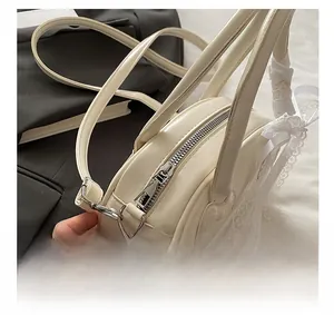 Close-up of smooth silver zipper and delicate lace bow details on the beige shell bag