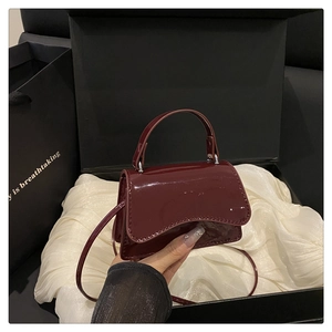 Close-up of glossy burgundy patent leather bag inside a luxury silk-lined gift box
