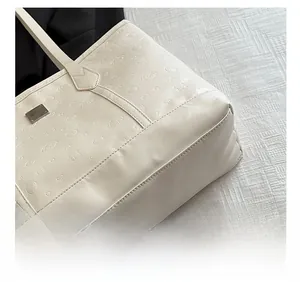 Detail of embossed puppy pattern and stitching on white leather tote bag