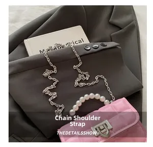 Detail of pink quilted crossbody bag with pearl handle and metal chain on a blazer