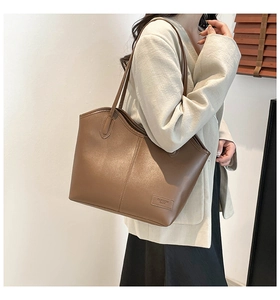 Close-up of brown PU leather tote bag with vertical stitching and long shoulder straps