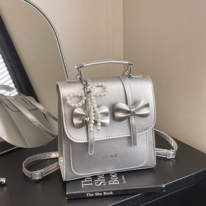 Silver bow backpack in metallic PU leather with pearl charm and fashion logo design