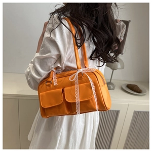 Détail du sac à main orange en similicuir avec nœuds en dentelle blanche et poches