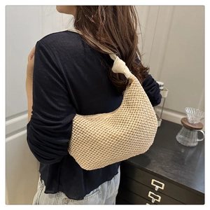 Detail of hand-woven crescent shoulder bag with knot handle in a beige straw design