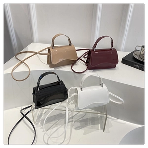 Mini patent leather crossbody bags in four colors displayed on white geometric stands