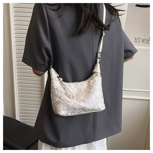 Close-up of beige shoulder bag with geometric patterns and beaded charms for summer
