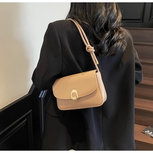 Beige leather underarm bag featuring a gold U-shaped buckle and knotted strap detail