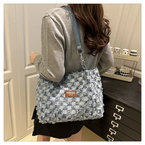 Blue and white checkered tote bag with fringe texture and leather logo tag on shoulder