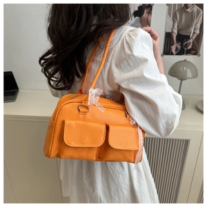 Détail d'un sac polochon orange vintage avec nœud en dentelle et doubles poches avant