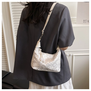 Detail of white jacquard texture underarm bag with refined floral patterns and thin strap
