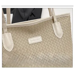 Detailed macro view of cream woven tote bag texture with fashion label and stitching