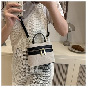 Detail of canvas vanity bag with black leather trim and metal dual-zip closure