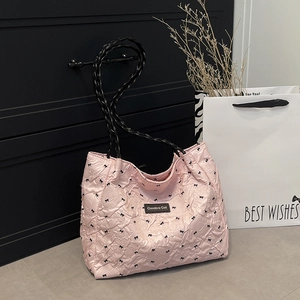 Pink quilted tote bag with black bow patterns and braided shoulder straps