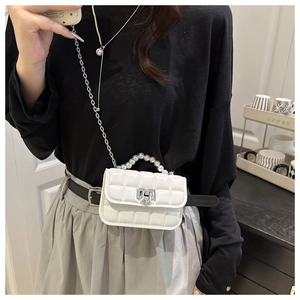 Detail of white quilted crossbody bag featuring elegant pearl handle and silver chain strap