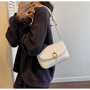 Detail of off-white shoulder bag with golden U-shaped buckle and knotted strap design